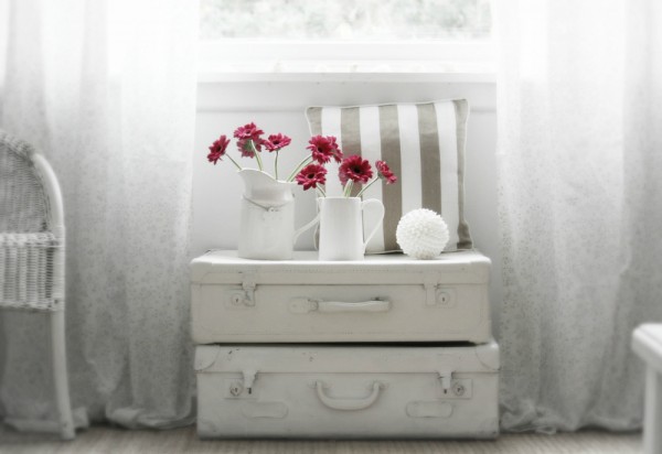 Un aranjament floral sub o fereastra luminat placut perfect in aerul rustic dat de valizele albe