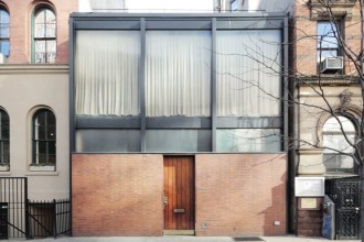 O casă din cărămidă și sticlă îngrămădită între alte două imobile