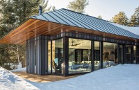 O casă de oaspeți construită pe structură metalică și înconjurată de pădurea din Vermont