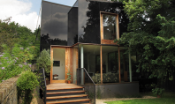 Anvelopantă din sticlă neagră pentru o casă dintr-o zonă protejată „Casa copac” este o creatie a