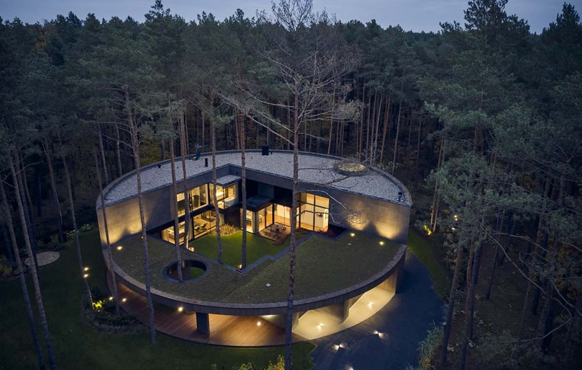 O casă circulară construită printre arbori într-o pădure de pini 