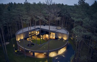 O casă circulară construită printre arbori într-o pădure de pini 